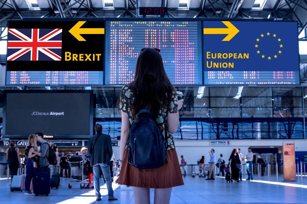 A picture of a woman a airport with her back to the camera. She is looking at an arrival/departures board. On the right, the board is covered with an arrows pointing right with "European Union" written on it and an EU symbol. On the left, the opposite but with Brexit and a Union Flag.