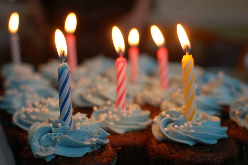 A close-up of cupcakes with burning candles on them.